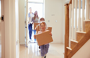 Family carrying boxes into new home