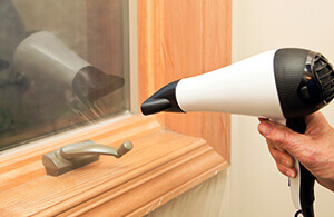 Using hair dryer to seal plastic to window