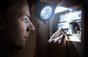 Man looking at breaker box with flashlight