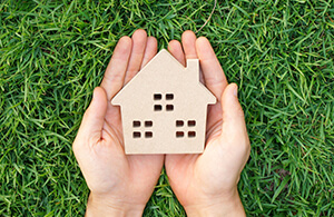 Hands holding miniature wooden house