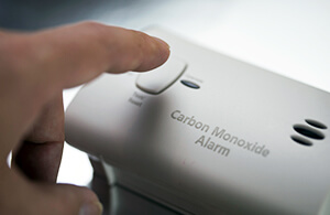 Hand pressing button on carbon monoxide tester