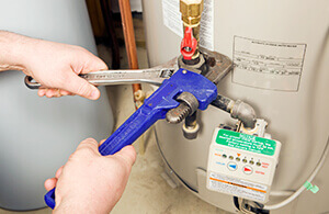 Person using 2 wrenches to fix a hot water heater