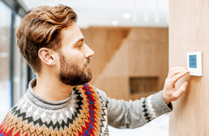 ai_heating_savetips_2 Man adjusting thermostat